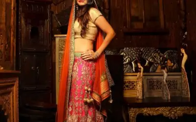 A woman in traditional Indian attire, wearing a colorful lehenga and a dupatta, posing elegantly.