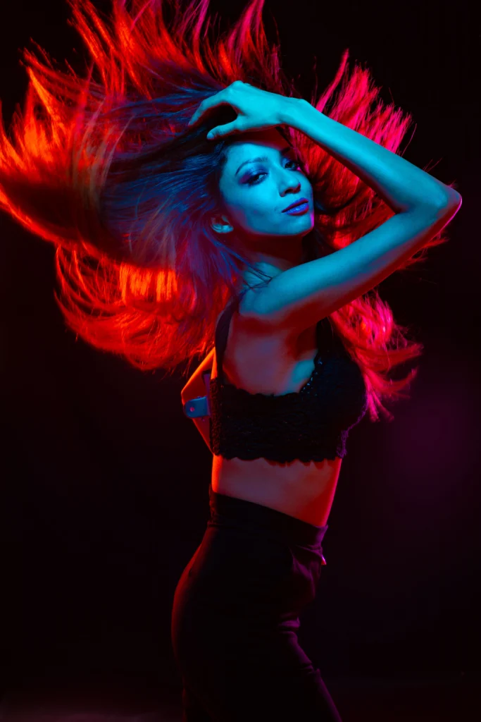 A dynamic image of a girl with vibrant red hair captured in mid-motion against a dark background, creating an impression of energy and movement.