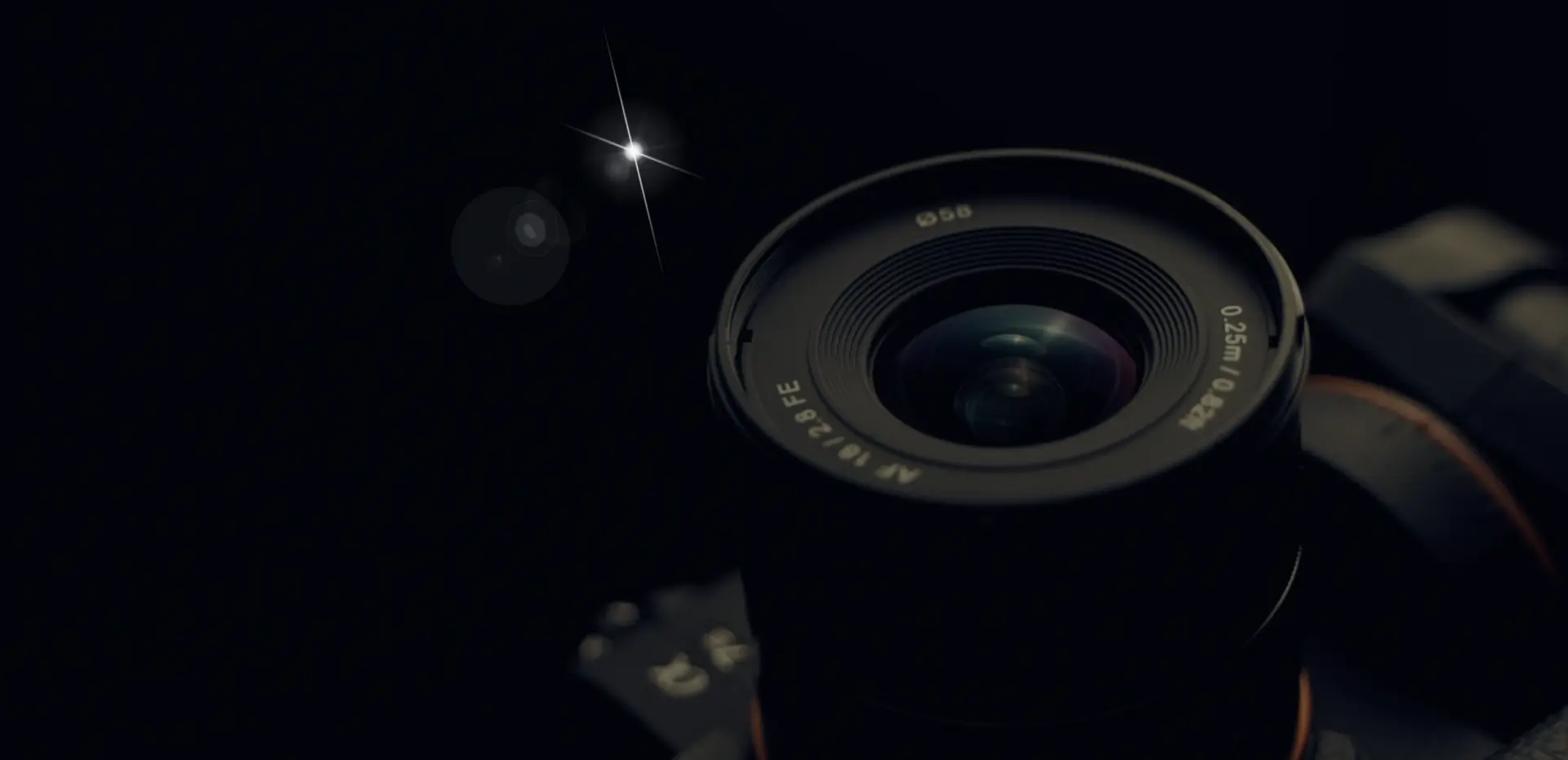 A close-up of a camera lens against a dark background, with light reflections.