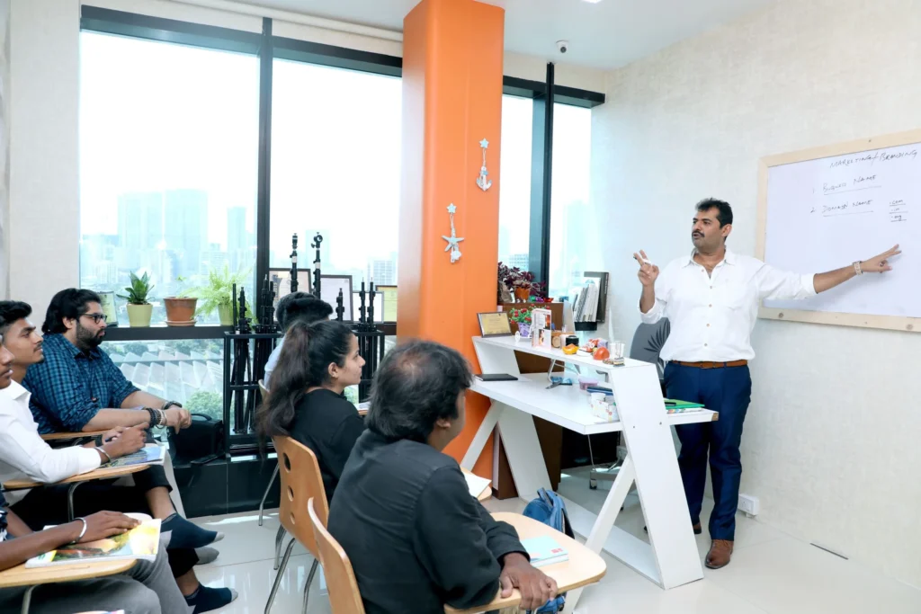 A man presenting in a classroom setting, with students seated and listening attentively.