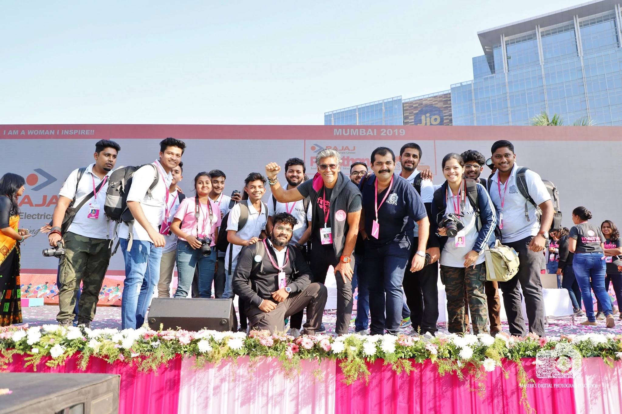 A group of people posing for a photo at an event, with a former model Milind Soman in the center