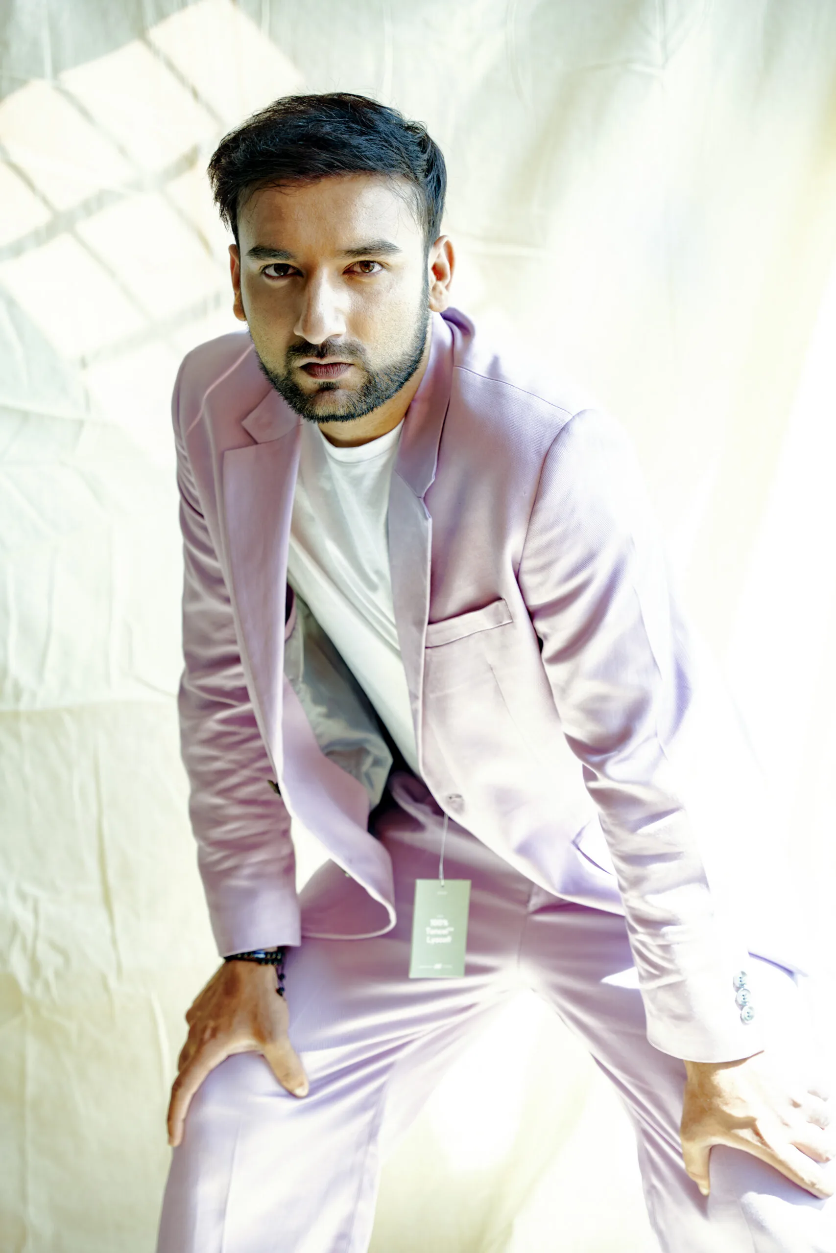 A man in a pastel pink suit striking a confident pose.