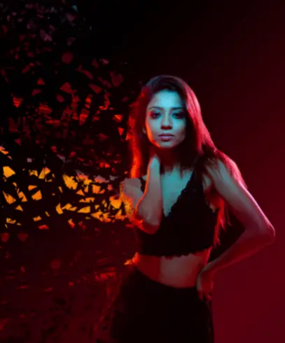 A woman in a black crop top posing against a colorful, abstract background.