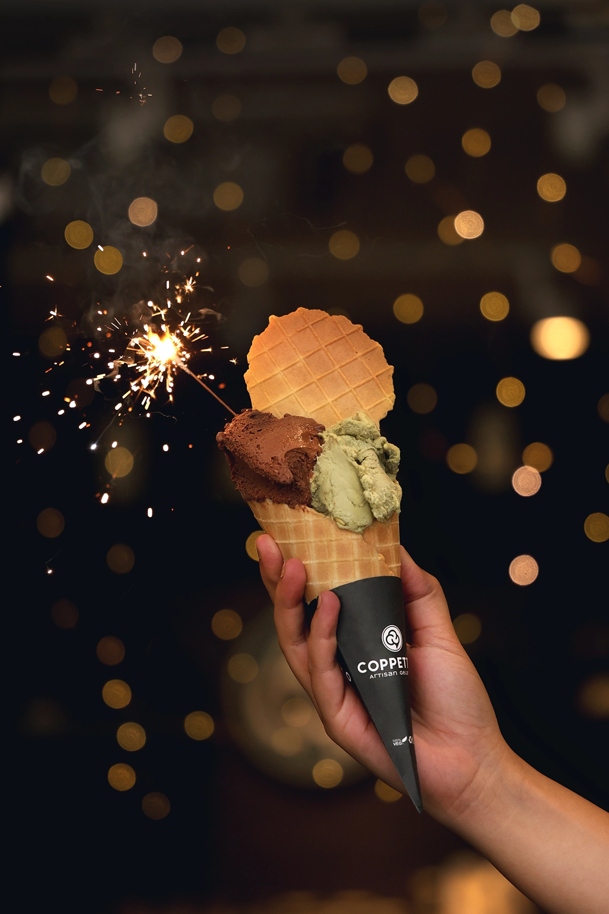 Product photography course student project featuring an artisan ice cream cone lit by a glowing sparkler against a bokeh background.