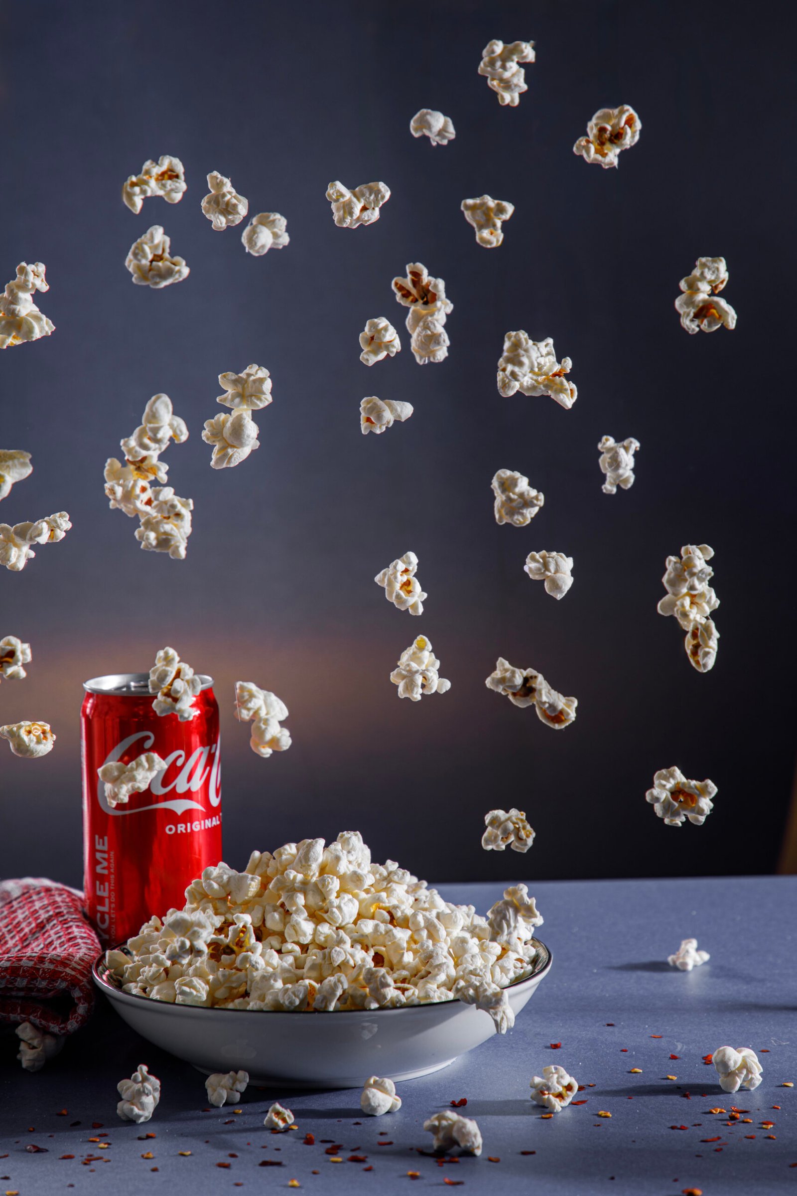 Product photography course student project capturing falling popcorn and a red soda can in action against a dark backdrop.